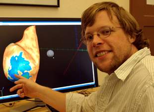 UO doctoral student Edward Ester points to a rendering of the brain's visual cortex on a computer screen display, where areas of brain activity are shown.
