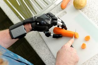 photo of a person wearing i-limb digits cutting carrots