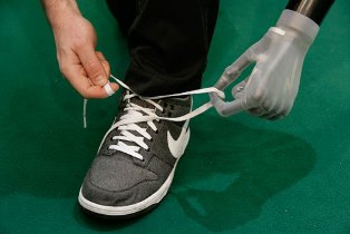 Photo of a person wearing an i-limb tying shoelaces